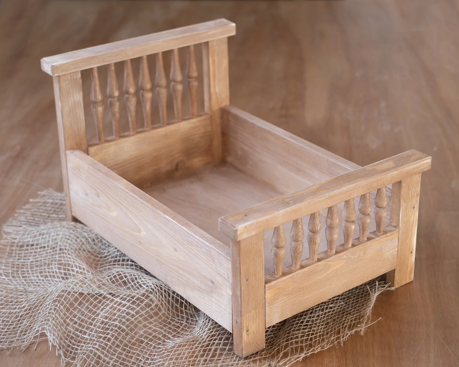 Világos barna, antikolt fa ágy esztergált díszítéssel újszülött fotózáshoz