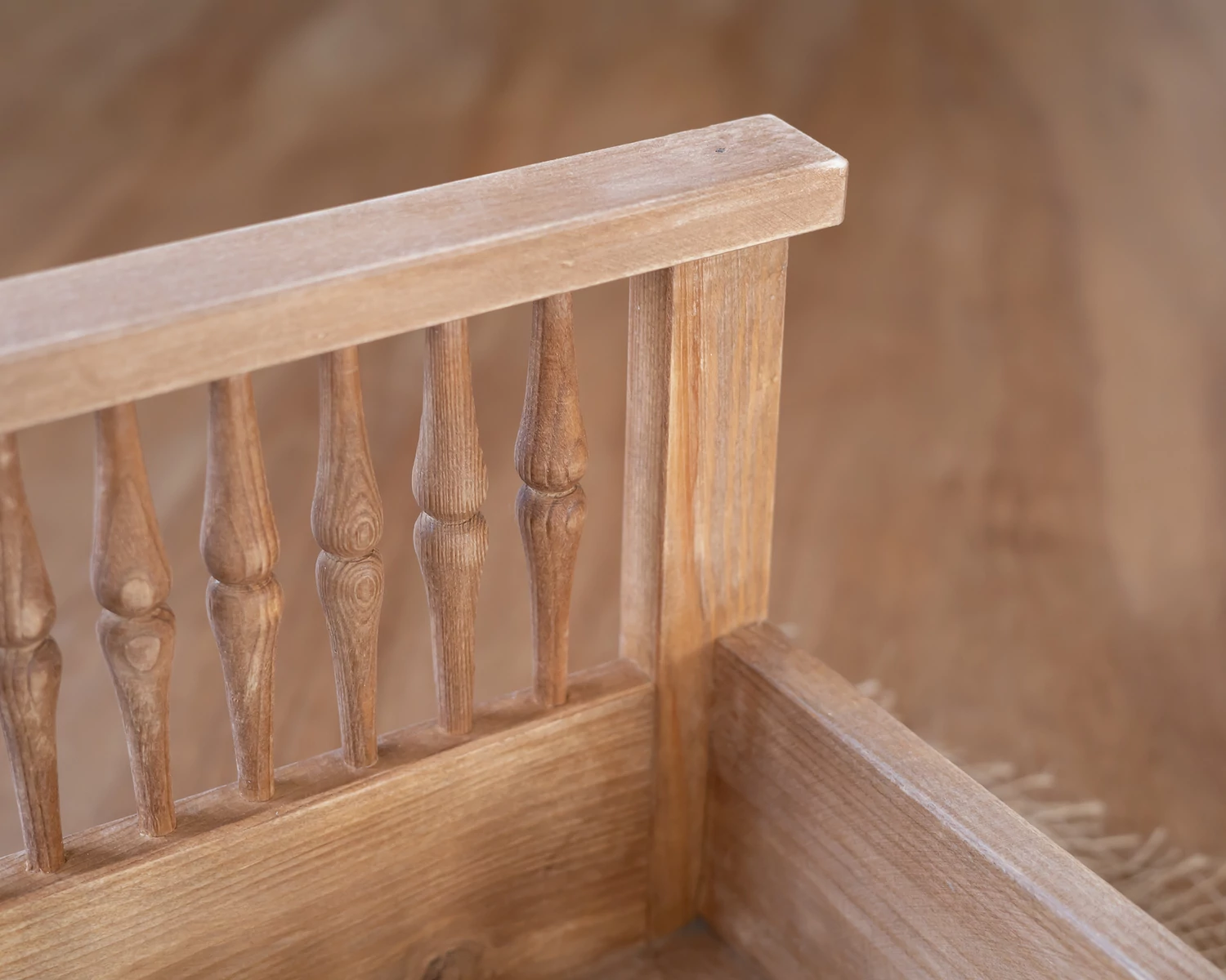 Világos barna, antikolt fa ágy esztergált díszítéssel újszülött fotózáshoz