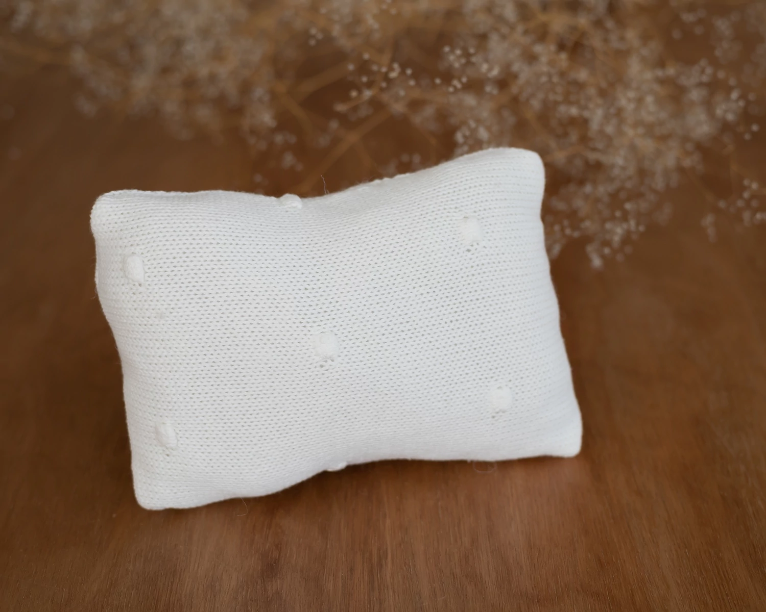 Törtfehér párna bogyós díszítéssel újszülött fotózáshoz